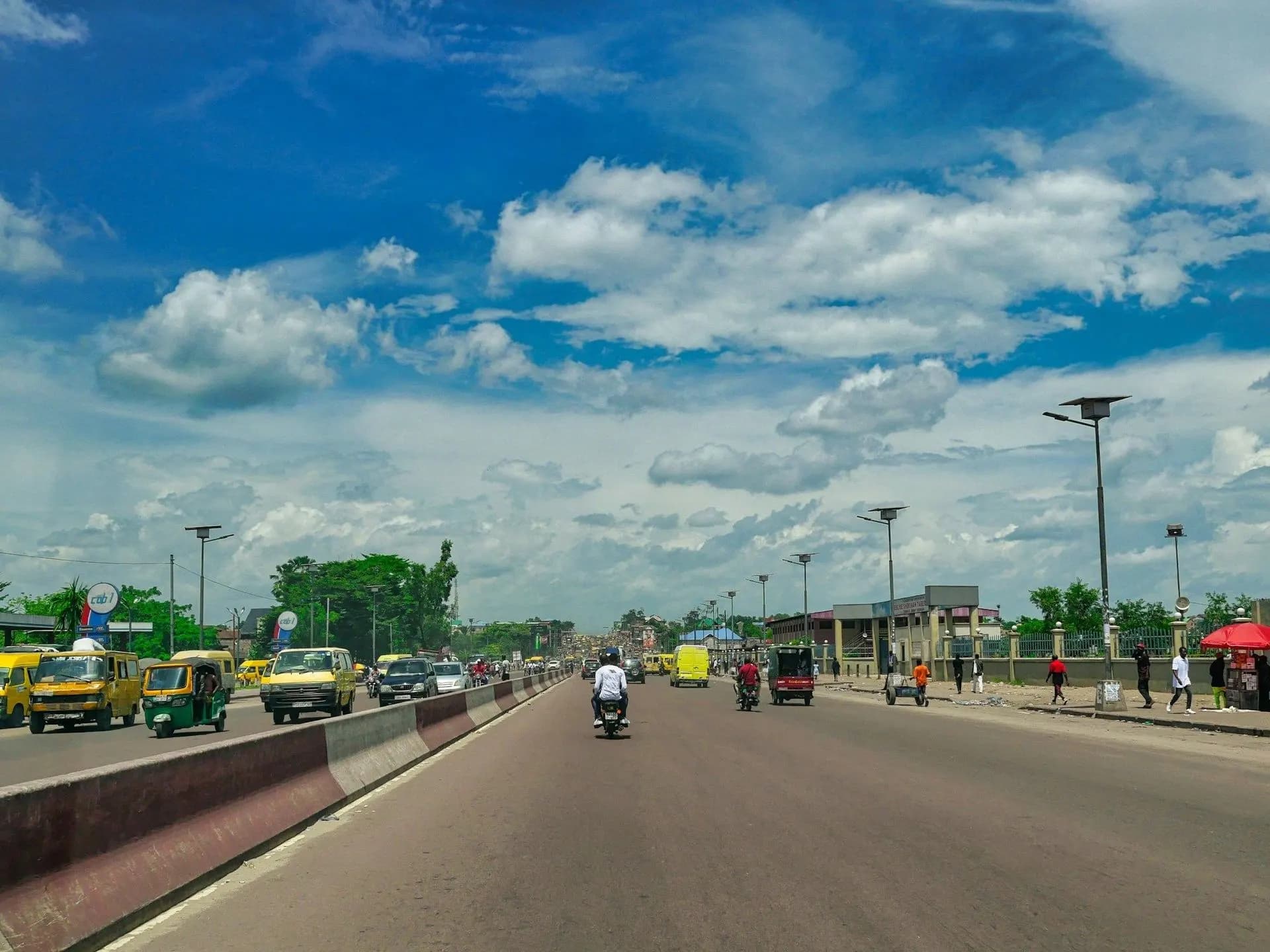 Boulevard de Kinshasa avec taxis jaunes et motos